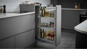 Premium three-tier stainless steel bottle basket pulling out of a modular kitchen cabinet carcass.