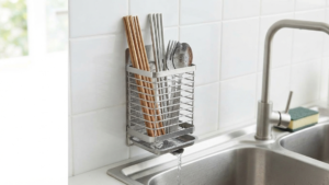 Vertical wall-mounted stainless steel chopstick holder draining over kitchen sink.