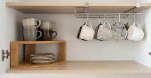 A deep, soft-close kitchen drawer in a modern Bangladeshi home, featuring a custom-fitted, dark gray antimicrobial insert that securely holds various sizes of crystal glassware and coffee cups, preventing movement and breakage.