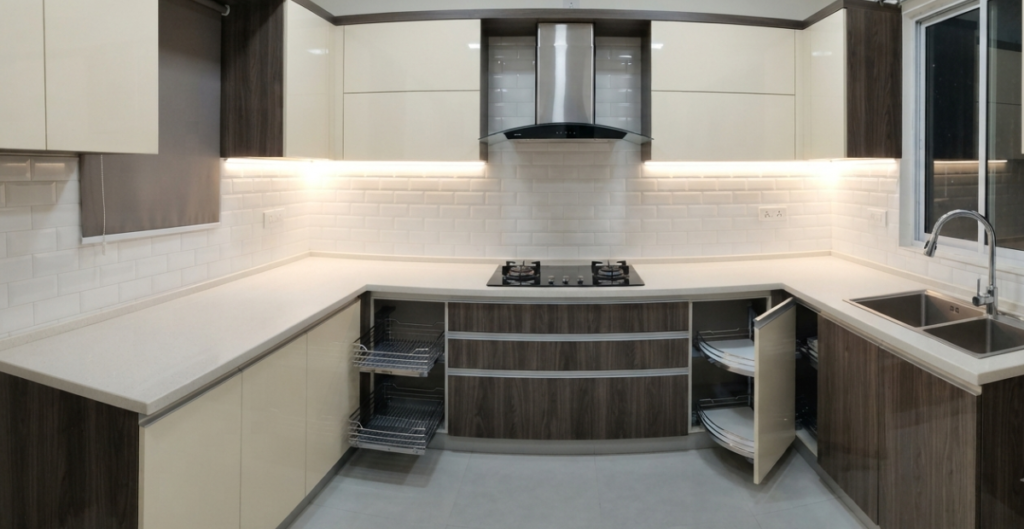 A newly installed modern modular kitchen in a Bangladeshi home featuring glossy cabinets, a built-in hob, range hood, and organized accessories.