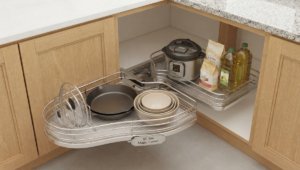 Close-up view of a specialized 3-sided U-shaped stainless steel pull-out basket installed beneath a kitchen sink, organizing cleaning supplies around plumbing pipes.